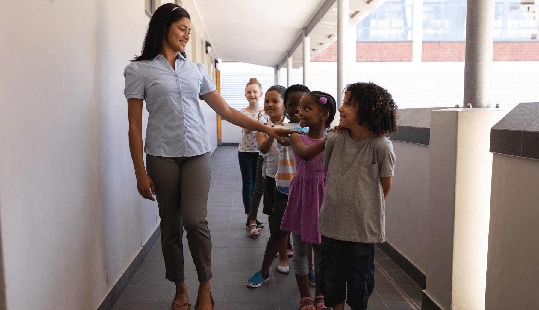 Schoolkids with teacher standing in row in hallway