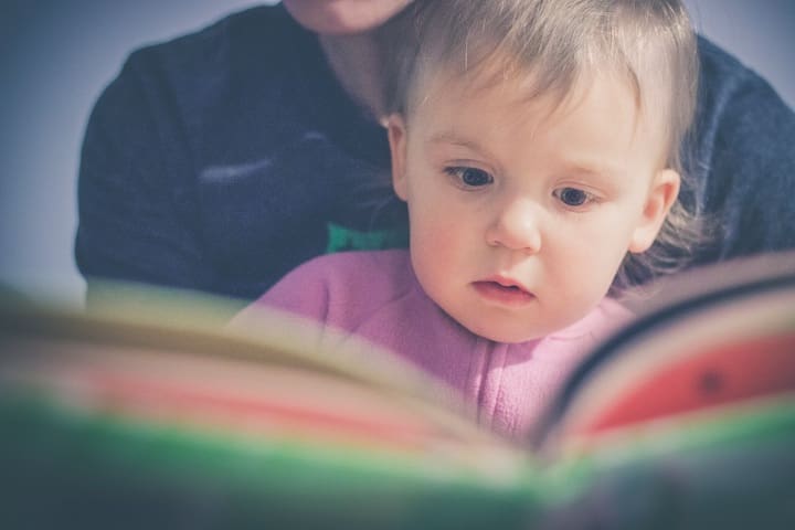 A parent holding their child while reading to them.