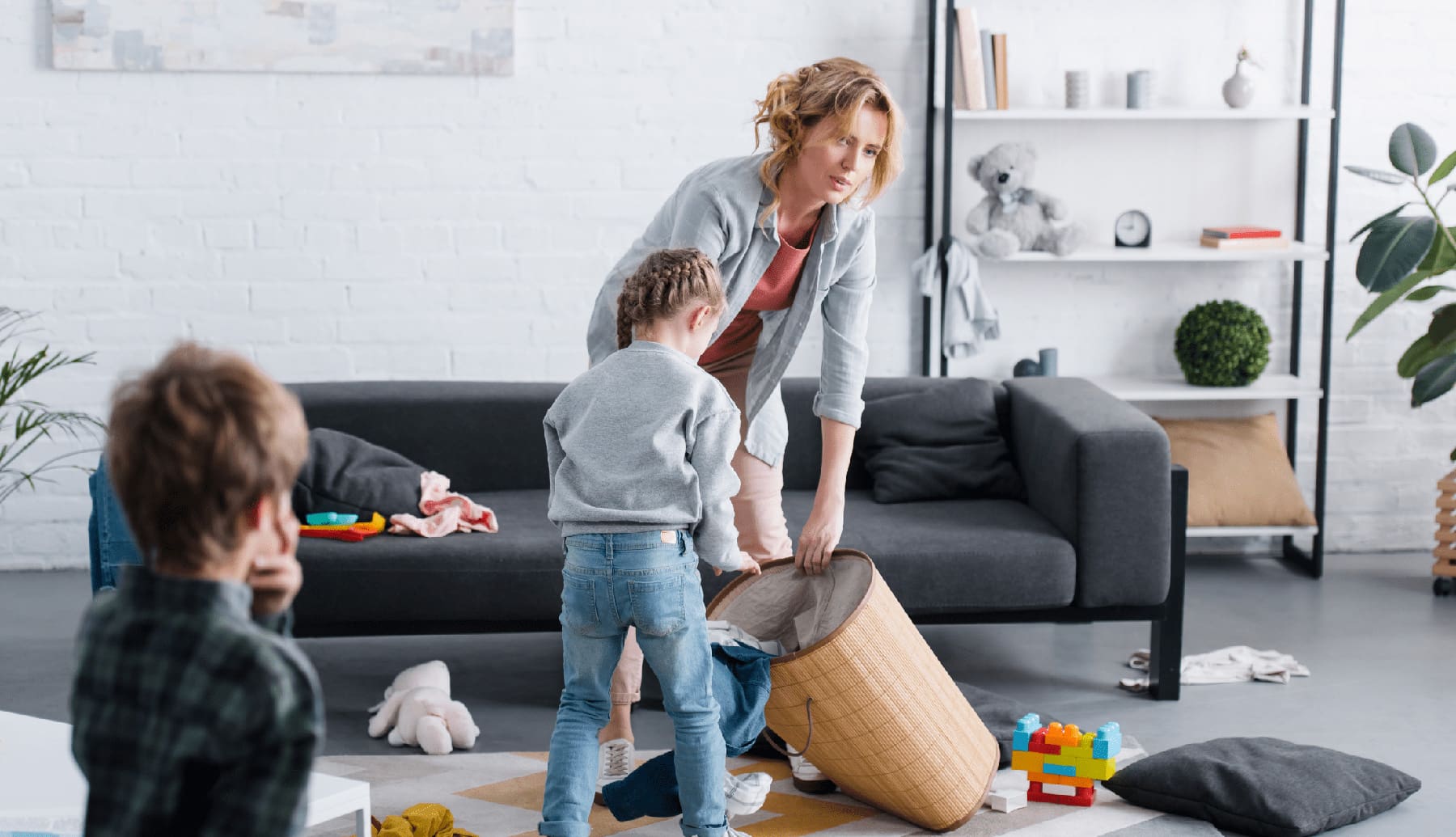tired mother putting toys in basket while naughty children playing at home | Difficult children