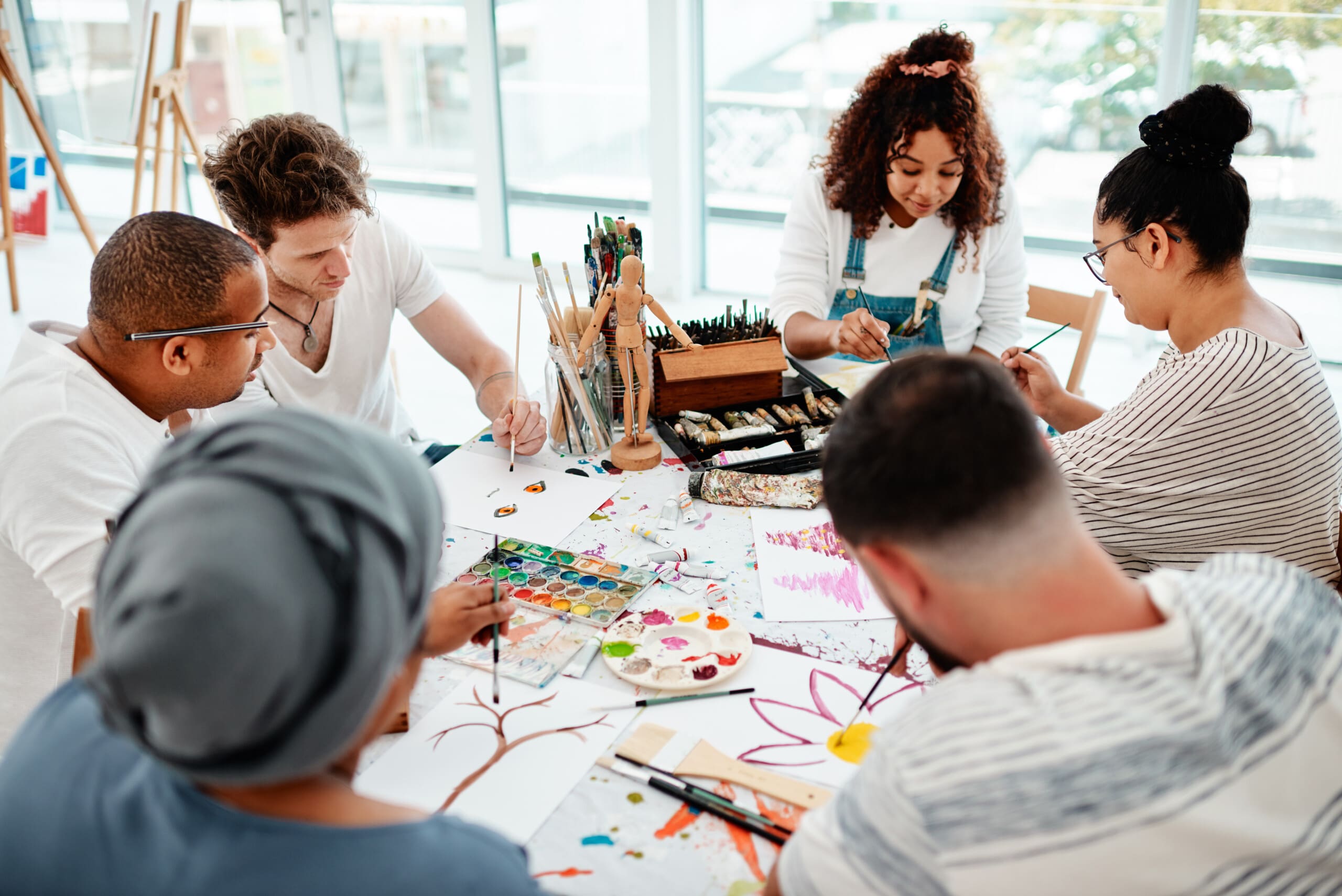 A group of young adults engaging in a group activity of painting and art therapy.