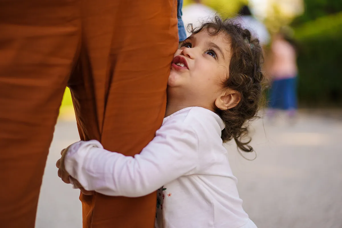 Young Mixed-Ethnicity Girl Embracing Mother's Leg