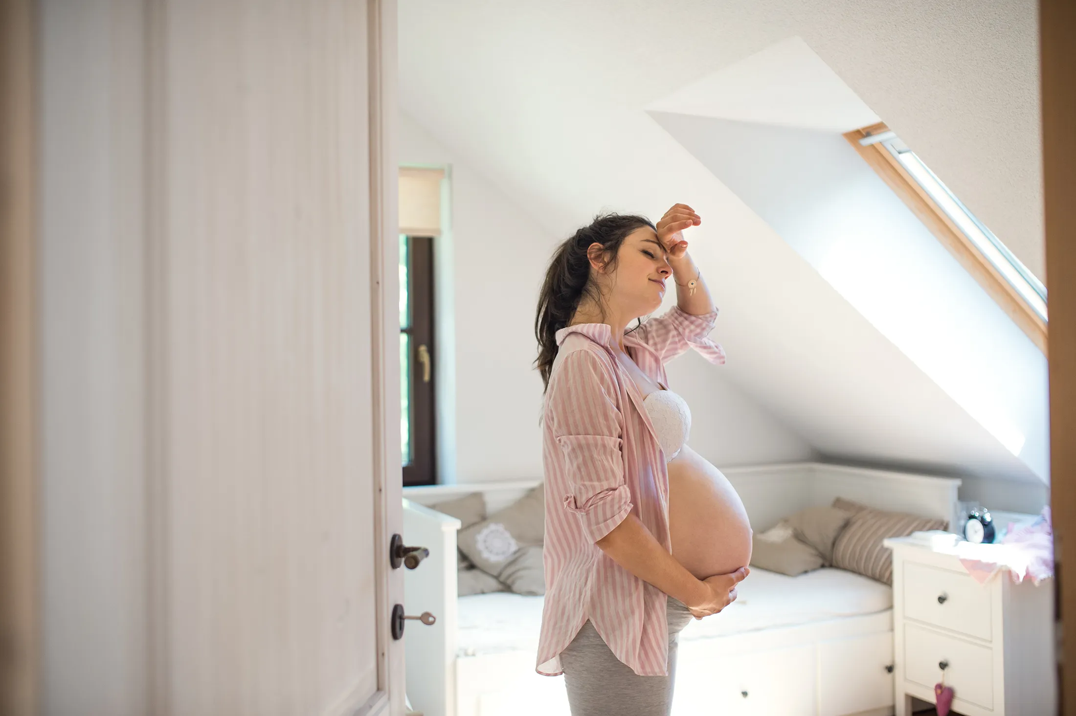 Portrait of tired pregnant woman indoors at home, holding head Pregnant woman feeling overwhelmed at home, representing perinatal mental health and therapy support for expectant mothers