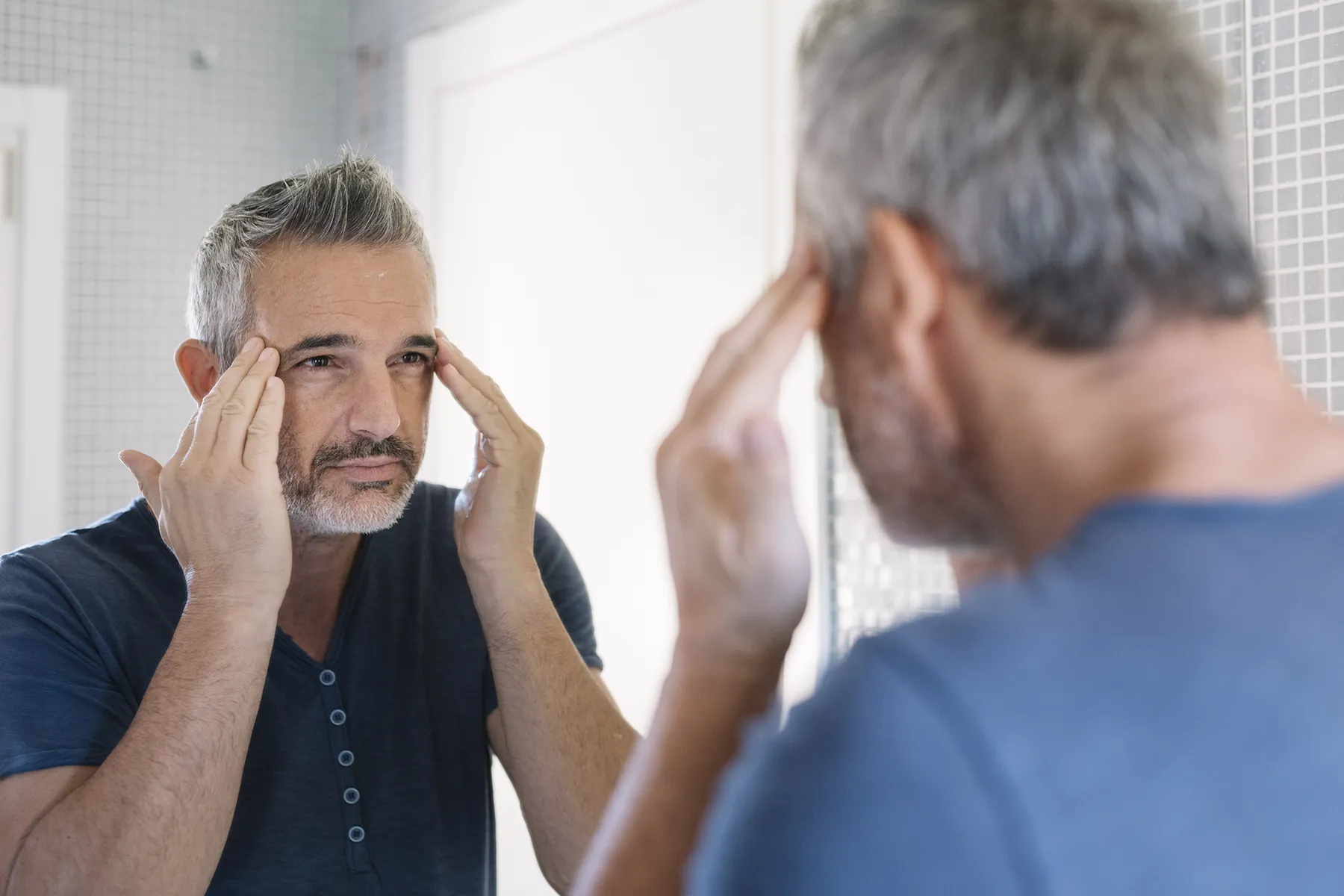 mature man looking in bathroom mirror