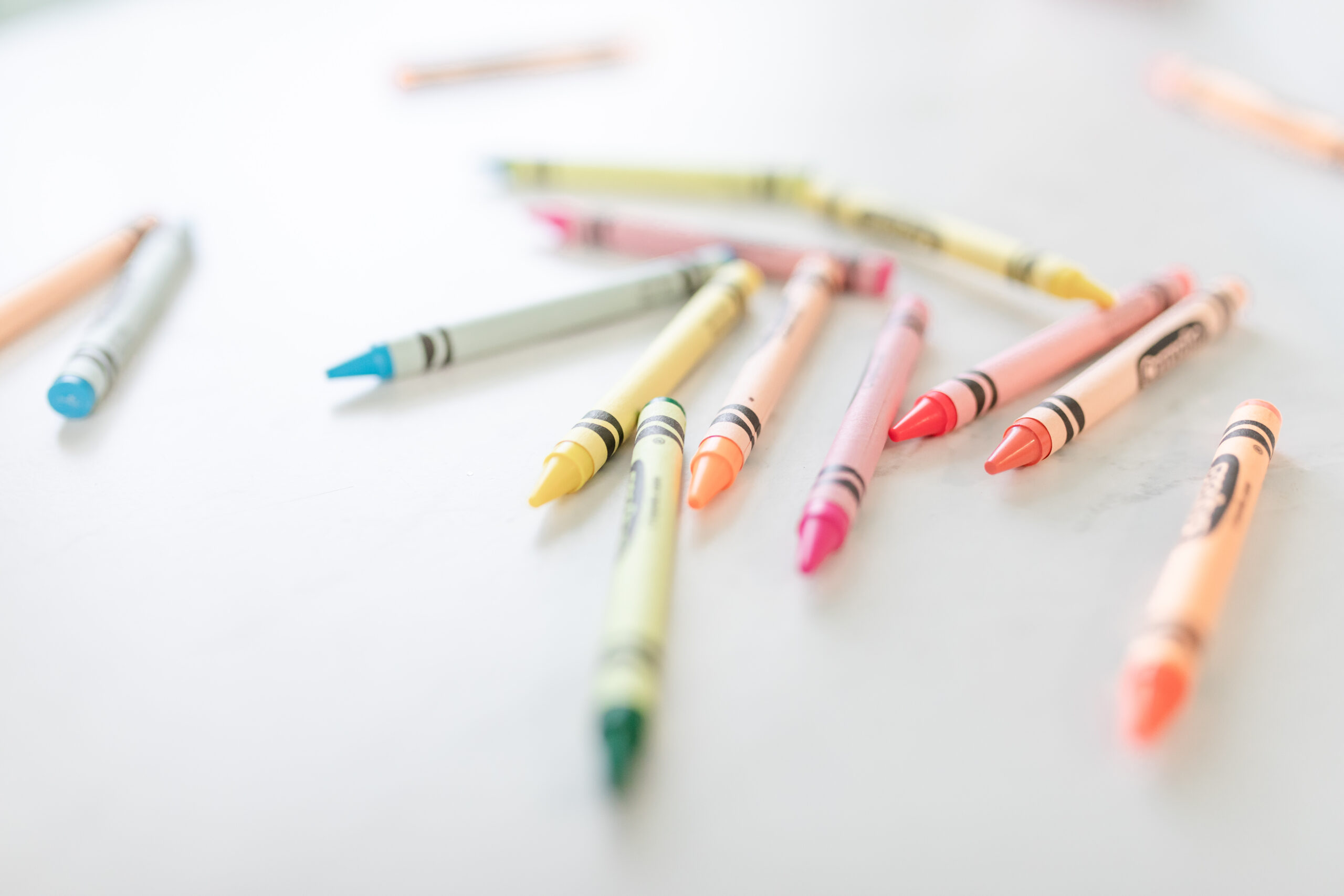 Colorful crayons scattered on a white surface, representing art-making and creative expression
